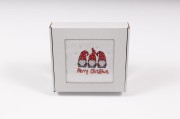 Elegancki świąteczny ręcznik frotte 500g z precyzyjnym haftem przedstawiającym trzy urocze krasnale i napis Merry Christmas, zapakowany w białe kartonowe pudełko z okienkiem, idealny na prezent pod choinkę.