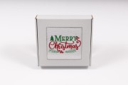 Elegancki świąteczny ręcznik frotte 500g z klasycznym haftem Merry Christmas i gałązkami ostrokrzewu, zapakowany w białe kartonowe pudełko z okienkiem, gotowy na prezent.