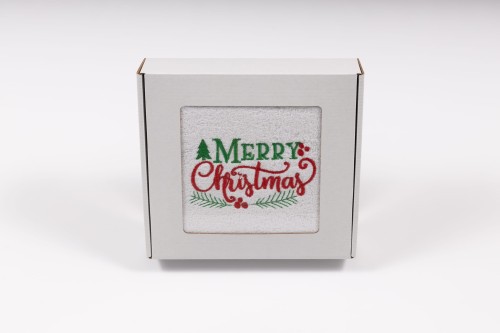 Elegancki świąteczny ręcznik frotte 500g z klasycznym haftem Merry Christmas i gałązkami ostrokrzewu, zapakowany w białe kartonowe pudełko z okienkiem, gotowy na prezent.