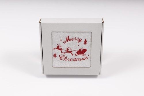 Elegancki świąteczny ręcznik frotte 500g z precyzyjnym haftem przedstawiającym sanie Mikołaja z reniferami i napis Merry Christmas, zapakowany w białe kartonowe pudełko z okienkiem, idealny na prezent.