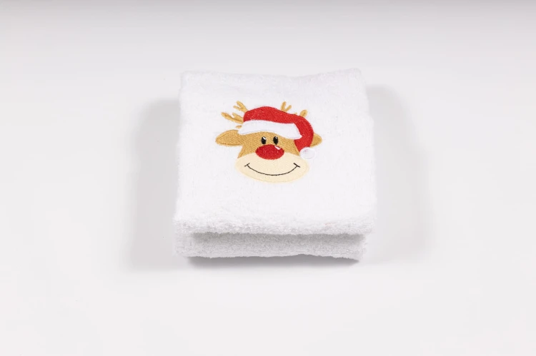 Elegancki świąteczny ręcznik frotte 500g z precyzyjnym haftem przedstawiającym uśmiechniętą głowę renifera w czerwonej czapce Mikołaja, idealny na prezent.