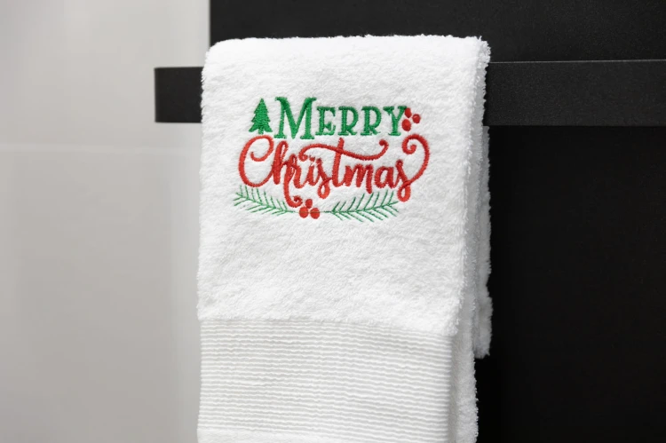 Miękki bawełniany ręcznik świąteczny 500 gsm z napisem Merry Christmas zawieszony na wieszaku w łazience