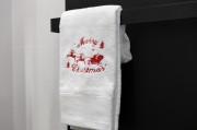 Miękki bawełniany ręcznik świąteczny 500 gsm z motywem reniferów i napisem Merry Christmas zawieszony na wieszaku w łazience