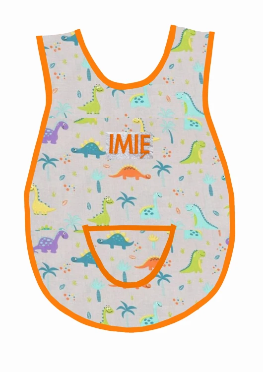 Bawełniany fartuszek do przedszkola z wzorem w dinozaury i z dużym personalizowanym haftem imienia oraz nazwiska dziecka, pomarańczowa lamówka