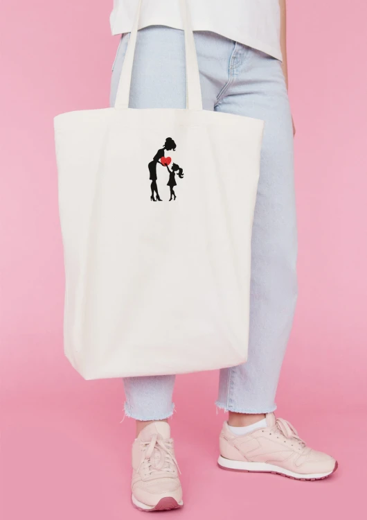 Kobieta niosąca torbę bawełnianą z personalizowanym haftem – praktyczny prezent na Dzień Mamy w użyciu.