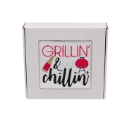 Biały ręcznik z haftem Grillin' and chilliin', zapakowany w białe pudełko z okienkiem.