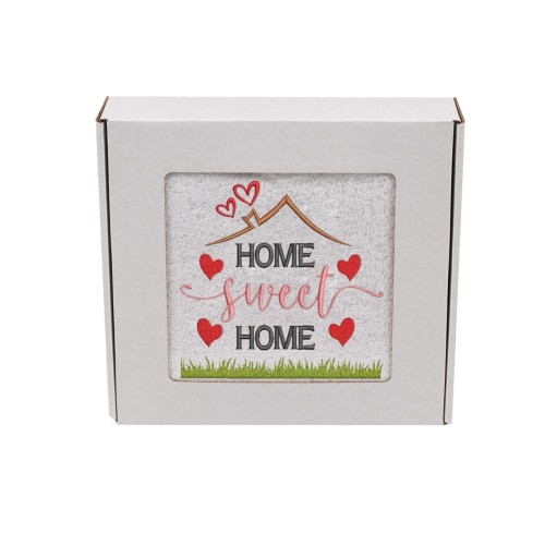 Biały ręcznik z haftem Home Sweet Home z motywem domu i serduszek zapakowany w ozdobne białe pudełko z okienkiem prezentowym.
