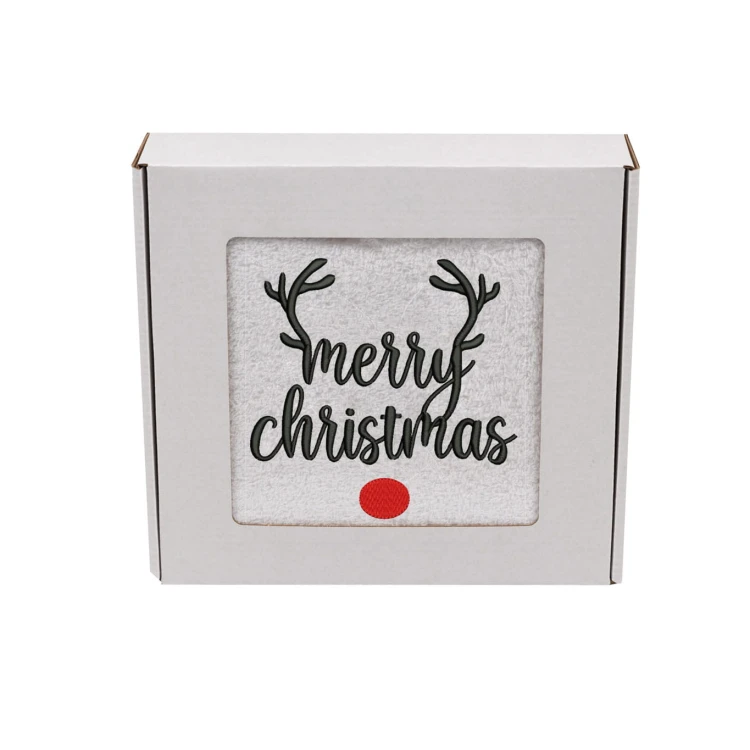 Elegancki świąteczny ręcznik frotte 500g z precyzyjnym haftem Merry Christmas, porożem renifera i czerwonym nosem, zapakowany w białe kartonowe pudełko z okienkiem, idealny na prezent.