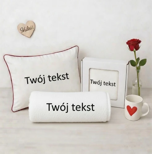 Zestaw prezentowy: poduszka dekoracyjna, ręcznik w eleganckim pudełku z okienkiem oraz ręcznik zwinięty w rulon – wszystkie produkty z personalizowanym haftem „Twój Tekst”.
