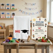 Biały ręcznik bawełniany 500g na Pasowanie na Przedszkolaka z personalizowanym haftem imienia dziecka i kolorową grafiką biretu.