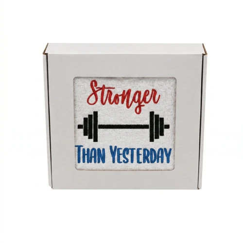 Biały personalizowany ręcznik bawełniany 500g z białym haftem przedstawiającym sztangę oraz napis „Stronger than Yesterday”, zapakowany w eleganckie pudełko z okienkiem.