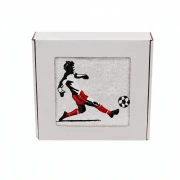 Biały personalizowany ręcznik bawełniany 500g z haftem przedstawiającym mężczyznę prowadzącego piłkę nożną, elegancko zapakowany w pudełko z okienkiem.