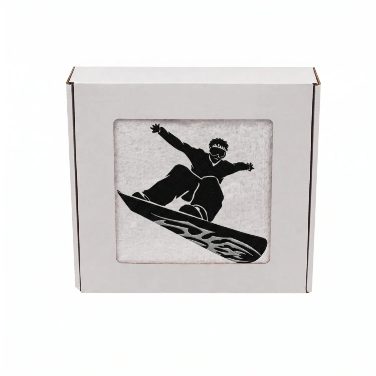 Biały personalizowany ręcznik bawełniany 500g z haftem przedstawiającym snowboardzistę wykonującego ewolucję na desce, zapakowany w eleganckie pudełko z okienkiem.