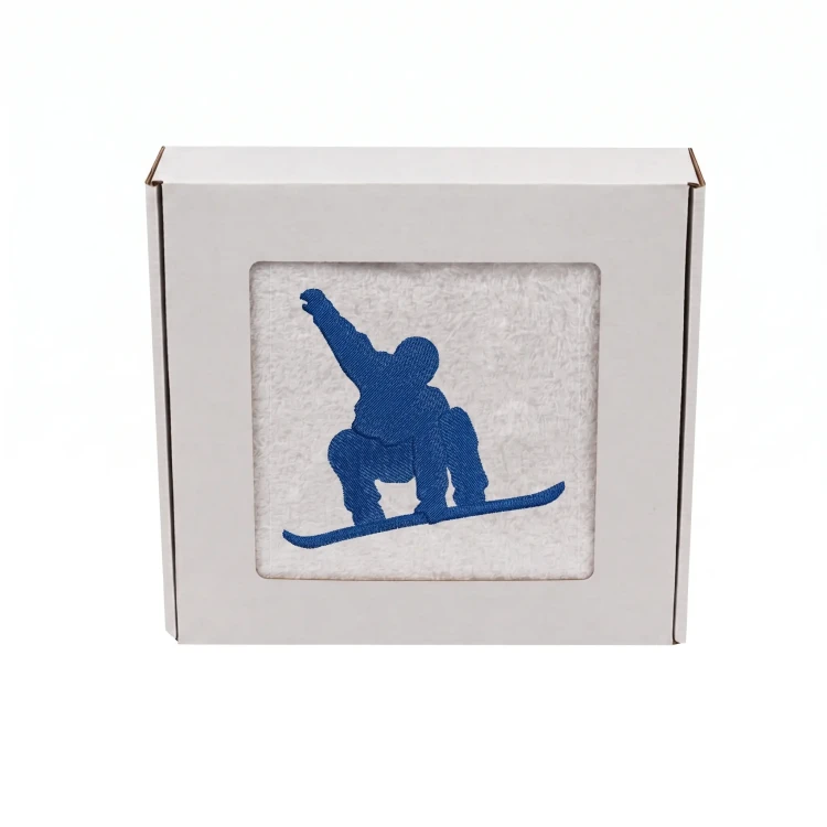 Biały personalizowany ręcznik bawełniany 500g z haftem przedstawiającym snowboardzistę wykonującego ewolucję na desce, zapakowany w eleganckie pudełko z okienkiem.