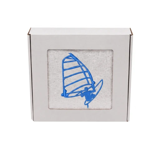 Biały personalizowany ręcznik bawełniany 500g z haftem przedstawiającym windsurfera płynącego na desce z żaglem, zapakowany w eleganckie pudełko z okienkiem.