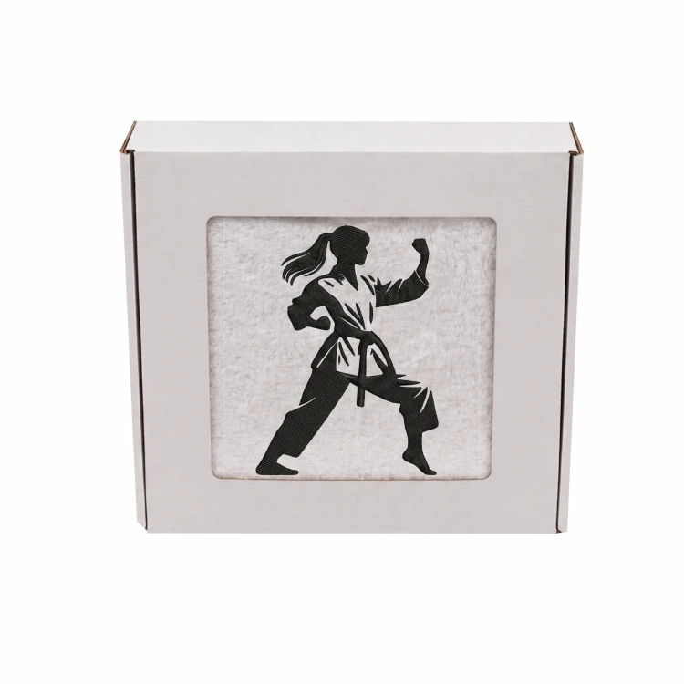 Biały personalizowany ręcznik 500g z haftem sylwetki kobiety w kimonie podczas treningu karate, wykonany ze 100% bawełny, umieszczony w estetycznym pudełku z okienkiem.