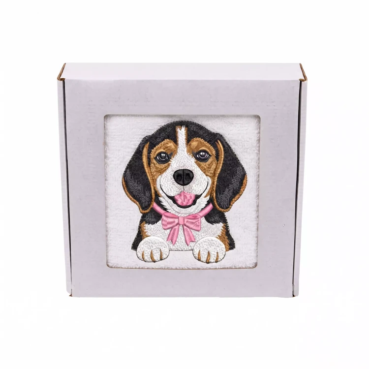 Personalizowany ręcznik frotte z precyzyjnym haftem przedstawiającym uroczego psa rasy beagle z różową muszką, zapakowany w białe pudełko z okienkiem.