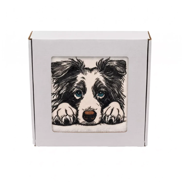 Personalizowany ręcznik frotte z precyzyjnym haftem przedstawiającym czarno-białego psa rasy border collie z inteligentnymi niebieskimi oczami i łapkami opartymi na krawędzi, zapakowany w białe pudełko z okienkiem