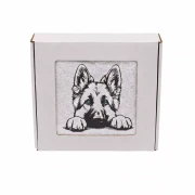 Personalizowany ręcznik frotte z precyzyjnym haftem przedstawiającym szczeniaka owczarka niemieckiego z charakterystycznymi stojącymi uszami i łapkami na krawędzi, zapakowany w białe pudełko z okienkiem.